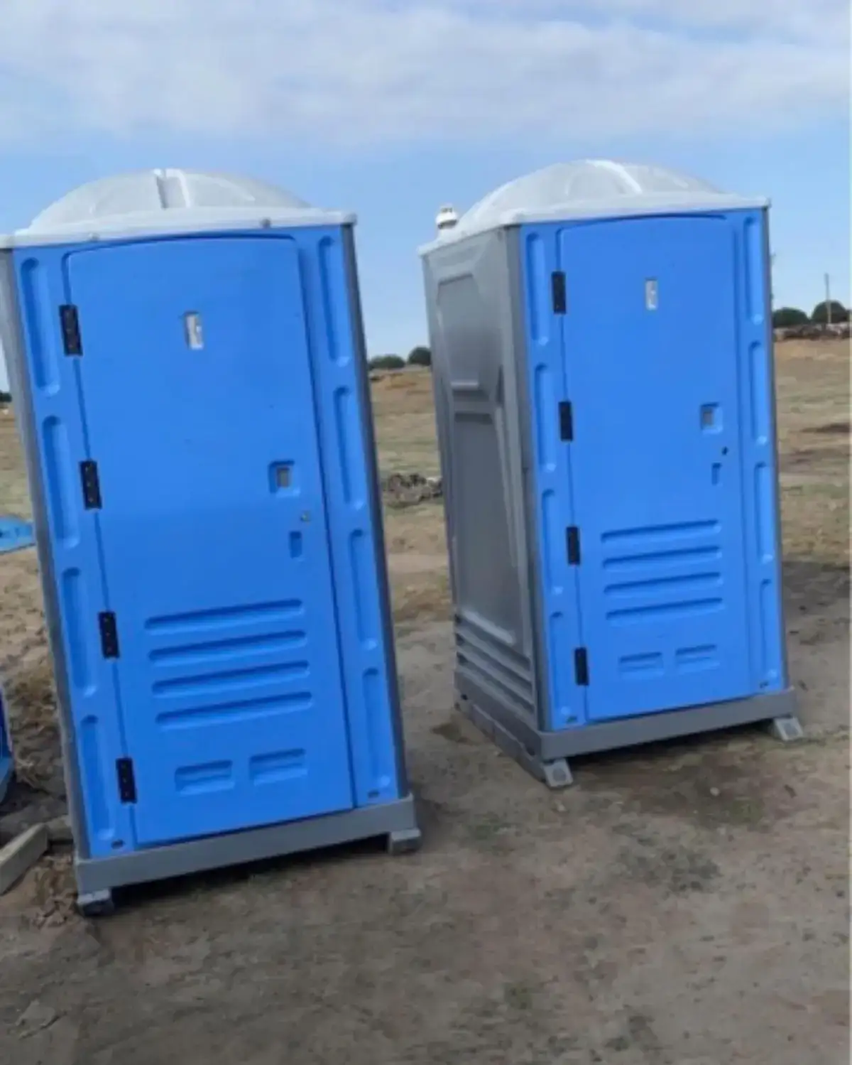Portable toilets standing on an open dirt lot