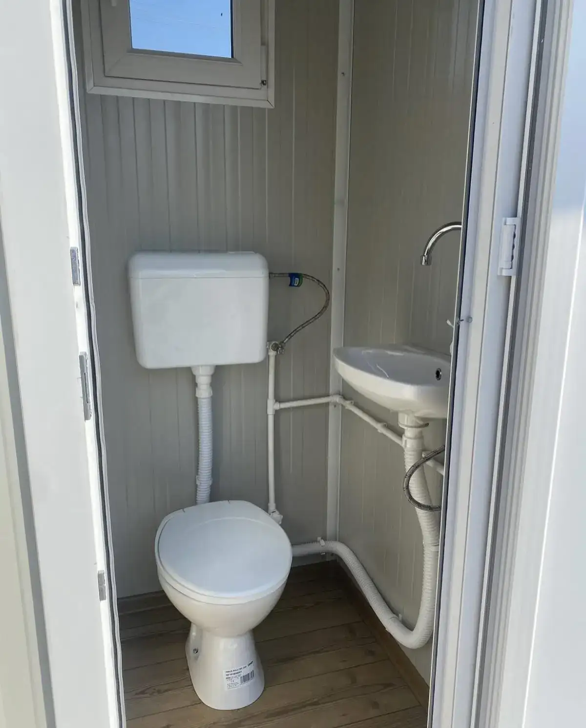 Interior of a flush restroom cabin with toilet and small sink