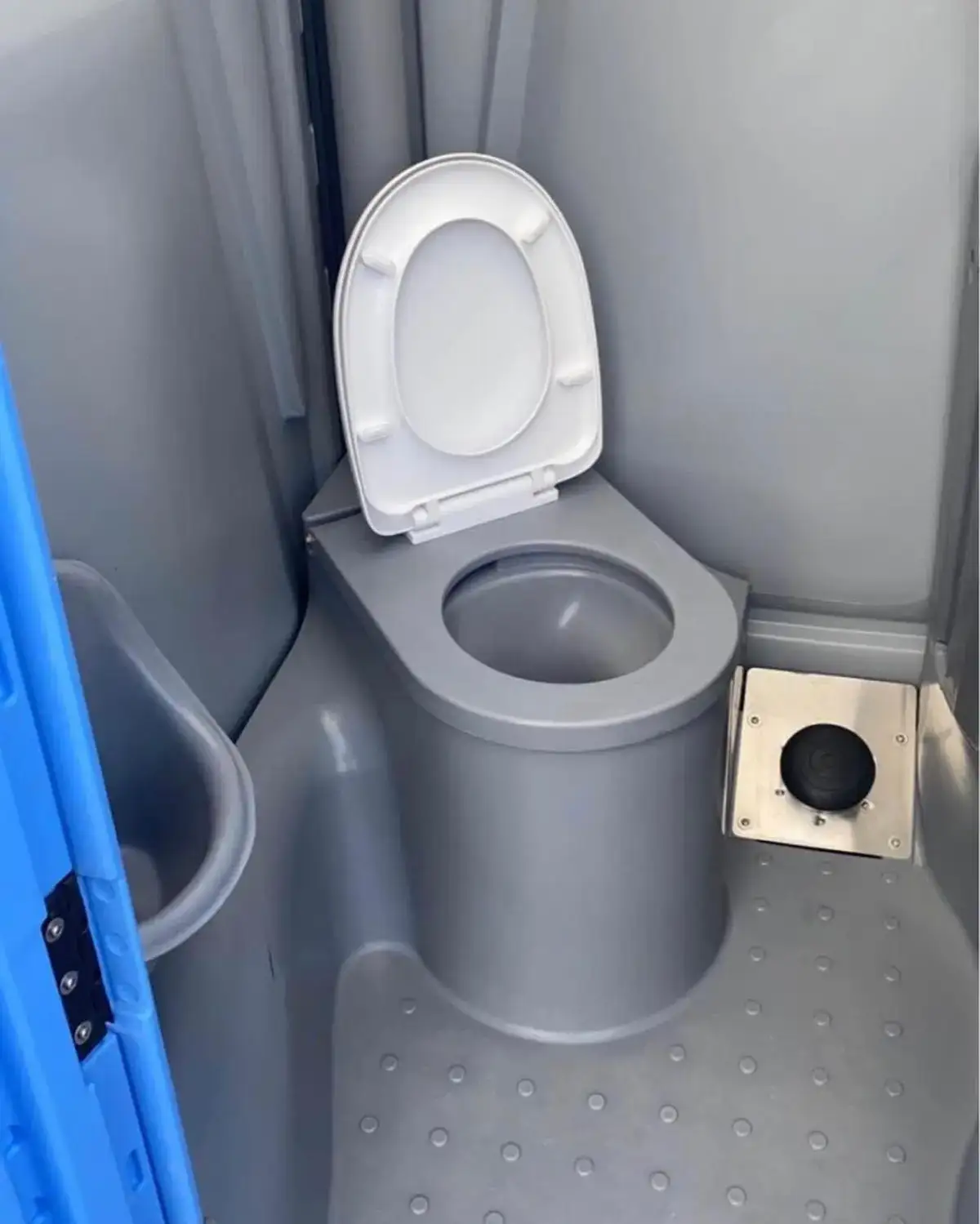 Inside a deluxe portable toilet with a white flush seat