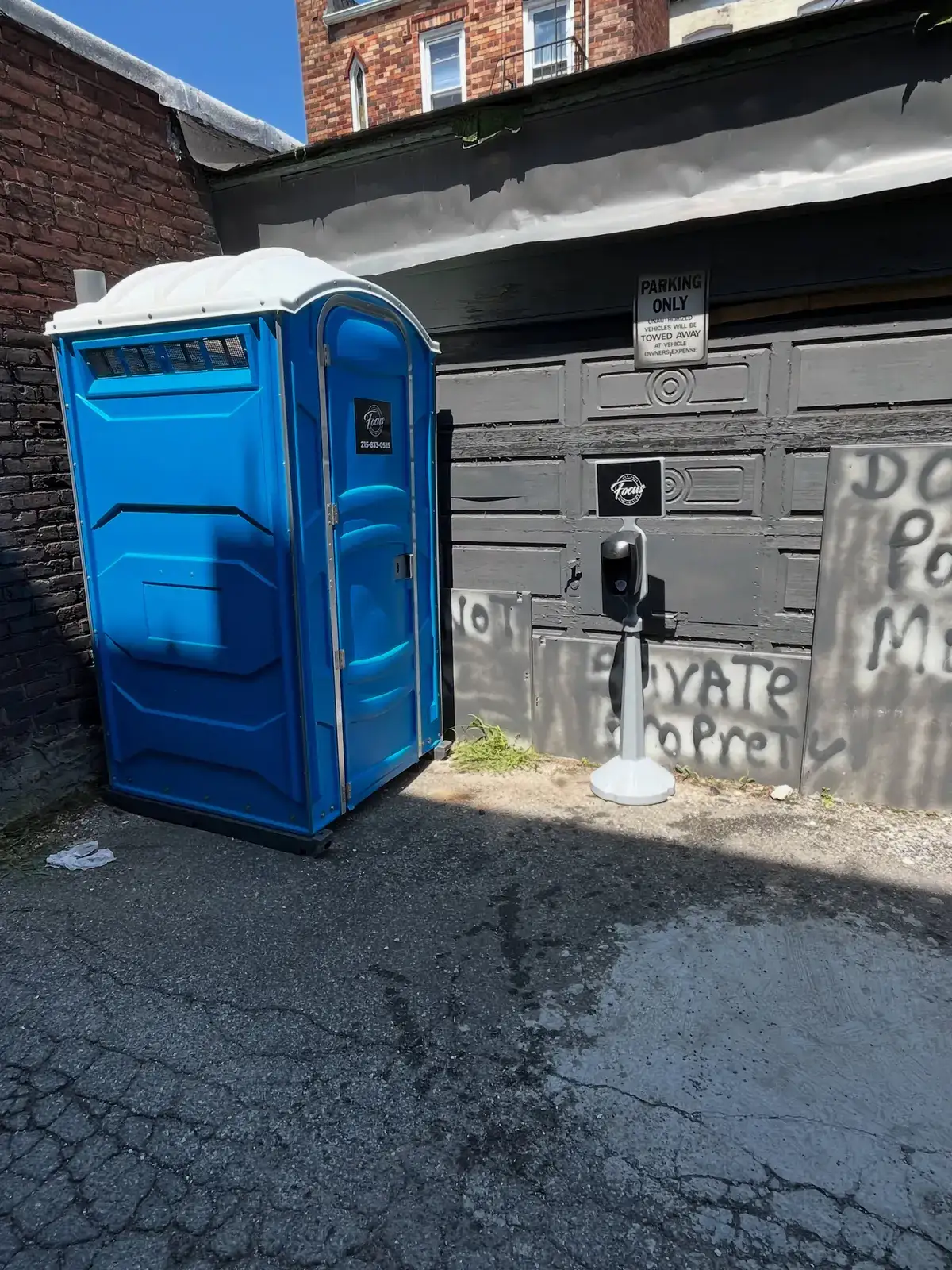 Portable toilet placed on private pavement behind a building