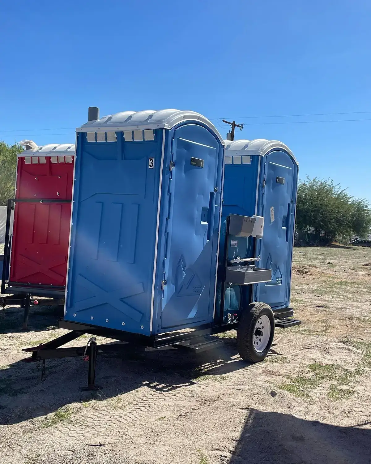 Portable toilets mounted on a small trailer at a job site